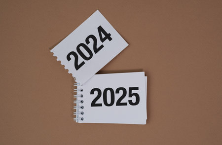 Two pieces of paper with the numbers 2024 and 2025 on them. The paper is torn and crumpledの写真素材