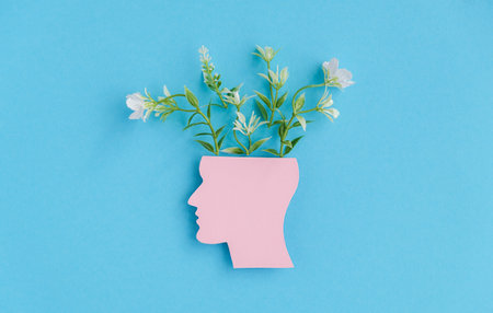 A head with a flower in it is on a blue background. The flower is in the middle of the head and is surrounded by a pink outline. Concept of creativity and imaginationの写真素材
