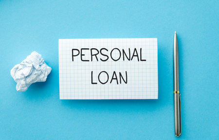 Thinking on Personal Loan, personal finance conceptual - handwriting on notepad with pan on blue backgroundの写真素材