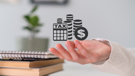 A hand holding a stack of money and a stack of tax forms. Concept of financial responsibility and the importance of paying taxesの写真素材