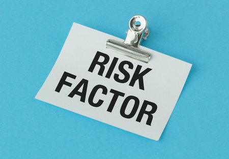 A clip holds a piece of paper that says Risk Factor. The clip is silver and the paper is white