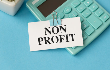A calculator sits on a blue surface with a white sign that says Non Profit on itの写真素材