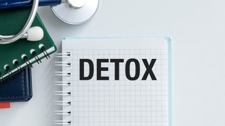 A medical journal with a pen and a stethoscope on top of it. The journal is titled Detox and has a grid pattern on the pagesの写真素材