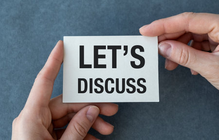 A hand holding a white card that says Let's discuss. Concept of collaboration and open communication