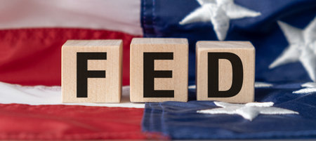 A wooden block with the letters FED on it, placed on top of a red, white, and blue American flag. The flag is positioned in the backgroundの写真素材