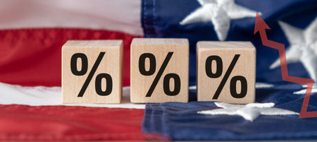 Three wooden blocks with a black and white percent sign on them are on top of a red, white, and blue American flagの写真素材