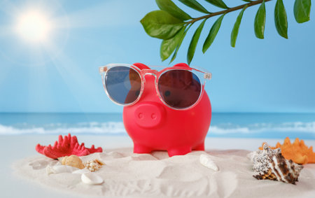 A red pig wearing sunglasses is sitting on a beach. The pig is wearing sunglasses and is enjoying the sunの写真素材