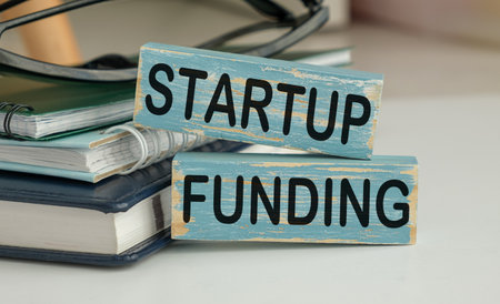 Holding wooden cube block with Startup Funding business word on table background. Marketing, Advertising and Product development conceptの写真素材