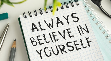 Notebook, the text always BELIEVE IN YOURSELF, next to glasses and pencils. Business Conceptの写真素材