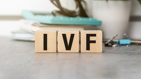 A wooden block with the letters IVF on it. The letters are black and white. The block is on a tableの写真素材