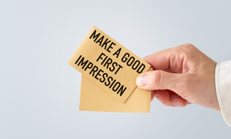A hand holding a piece of paper that says Make a Good First Impression. The paper is folded in half and the person is holding it upの写真素材