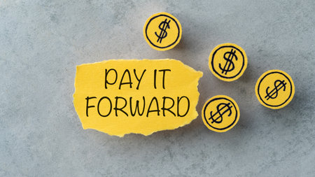 A yellow piece of paper with the words Pay it Forward written on it. There are also several coins scattered around the paperの写真素材