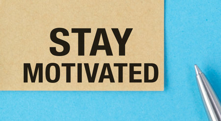 A piece of paper with the words Stay Motivated written on it. A pen is sitting on top of the paperの写真素材