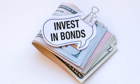 A stack of money with a sign that says Invest in Bonds. Concept of financial investment and the importance of making smart financial decisionsの写真素材