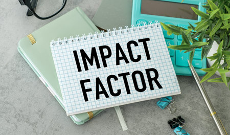 A notebook with the word Impact Factor written on it. The notebook is on top of a calculator and a pair of glassesの写真素材