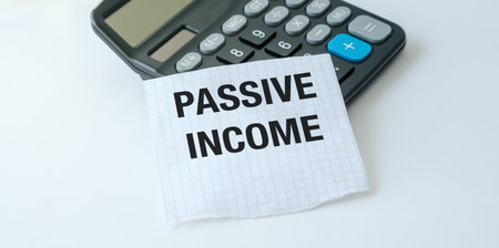 A calculator sits on a table with a piece of paper that says Passive Income. Concept of financial...