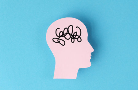 A head with a brain that is tangled and messy. The head is on a blue background. The brain is...
