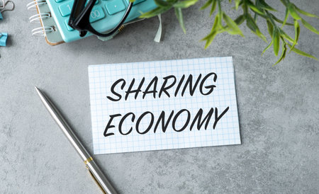 A pen is on a table with a piece of paper that says Sharing Economy. The pen is silver and has a gold tipの写真素材