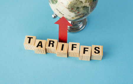 A wooden block with the word Tariffs written on it. The block is on top of a globe