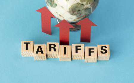 A globe is on top of a wooden block with the word Tariffs written on it. The globe is surrounded by three arrows pointing upwardsの写真素材