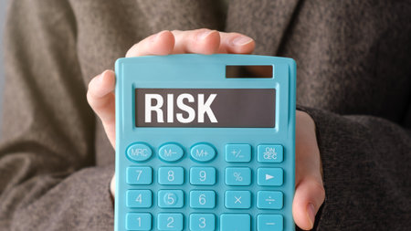 A blue calculator with the word RISK written on it. A person is holding the calculatorの写真素材