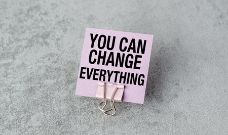 A pink card with the words You can Change Everything written on it. The card is held in place by a paper clipの写真素材