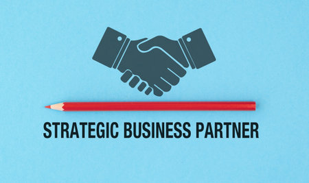 A red pencil is next to a handshake symbol. The text reads Strategic Business Partner. The image is blue in colorの写真素材