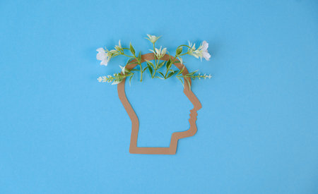 A head with flowers on it. The head is on a blue background, Mental Health Conceptの写真素材