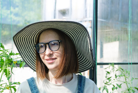 A woman wearing a straw hat and glasses. She is smiling. The hat is black and whiteの写真素材