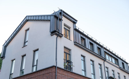A large building with a brick facade and a metal roof. The roof has a metal railing. The building has a lot of windowsの写真素材