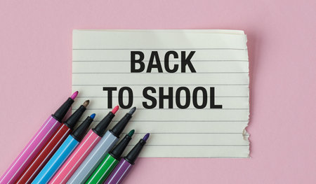 A sheet of paper with the words Back to School written on it. There are six markers on the paperの写真素材
