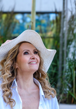 A woman wearing a white hat and a white shirt. She is smiling. The hat is white and has a pattern.の写真素材