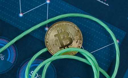 A coin with the letter B on it is on a green string. The string is on a blue piece of paper