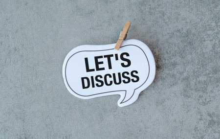 A white sign that says Let's Discuss is hanging from a clothespin. The sign is attached to a gray...