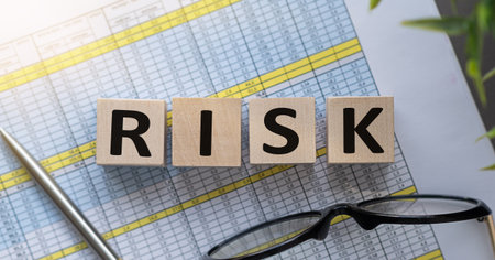 A wooden block with the word RISK written on it. The block is placed on top of a sheet of paper with...