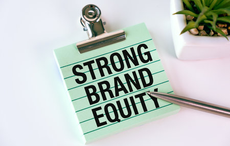 A clip board with the words Strong Brand Equity written on it. A pen is sitting on top of the clip boardの写真素材