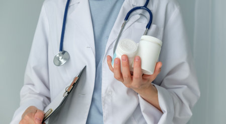A doctor is holding a clipboard and two white containers. Scene is serious and professionalの写真素材