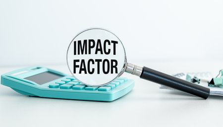 A calculator sits on a table with a magnifying glass and the word Impact Factor written on itの写真素材