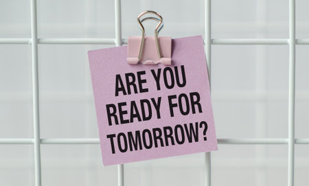 A pink sign that says Are you ready for Tomorrow is hanging on a white metal fenceの写真素材