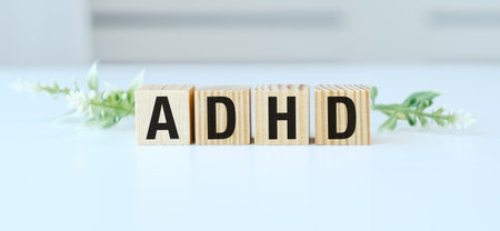 A wooden block with the letters ADHD on it. The letters are arranged in a way that they spell out the word ADHDの写真素材