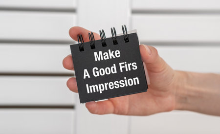 A hand holding a black notebook with the words Make a Good Impression written on it