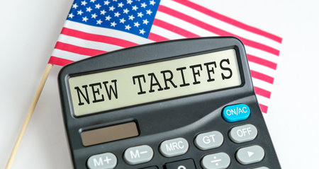 A calculator with the word New Tariffs written on it. The calculator is sitting on a flagの写真素材