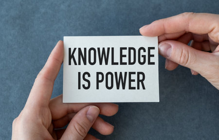 Knowledge is Power close up of a phrase being typed and centered on paper card in hand on gray backgroundの写真素材