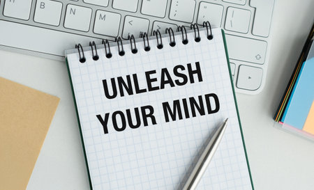 A spiral notebook with the words Unleash Your Mind written on it. A pen is sitting on top of the notebookの写真素材