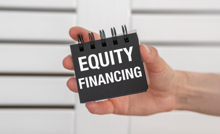 A hand holding a black notebook with the words Equity Financing written on itの写真素材