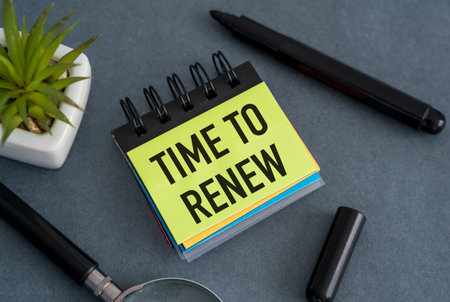 Time to Renew text on open notebook with magnifying glass, marker and flower on grey table, Business Conceptの写真素材