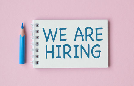 Job recruiting advertisement represented by WE ARE HIRING texts at note. Image is used to represent the hiring position to be recruited and filled.