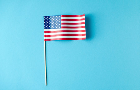 Miniature American flag on clean blue background emigration concept