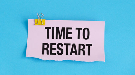 A pink piece of paper with a yellow clip holding it. The paper has the word Time To Restart written...