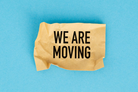 A torn piece of paper with the words We are Moving written on it. The paper is crumpled and has a...